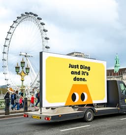 The Ding mascot on a billboard in front of the London Eye. The billboard reads: Just Ding and it's done.