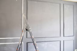 A half-done room with unpainted wooden panelling and unfinished walls, showing visible signs of a paused DIY decorating project.