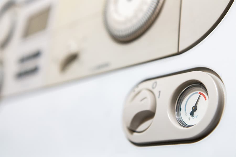 A boiler control panel with a pressure gauge indicating high boiler pressure.