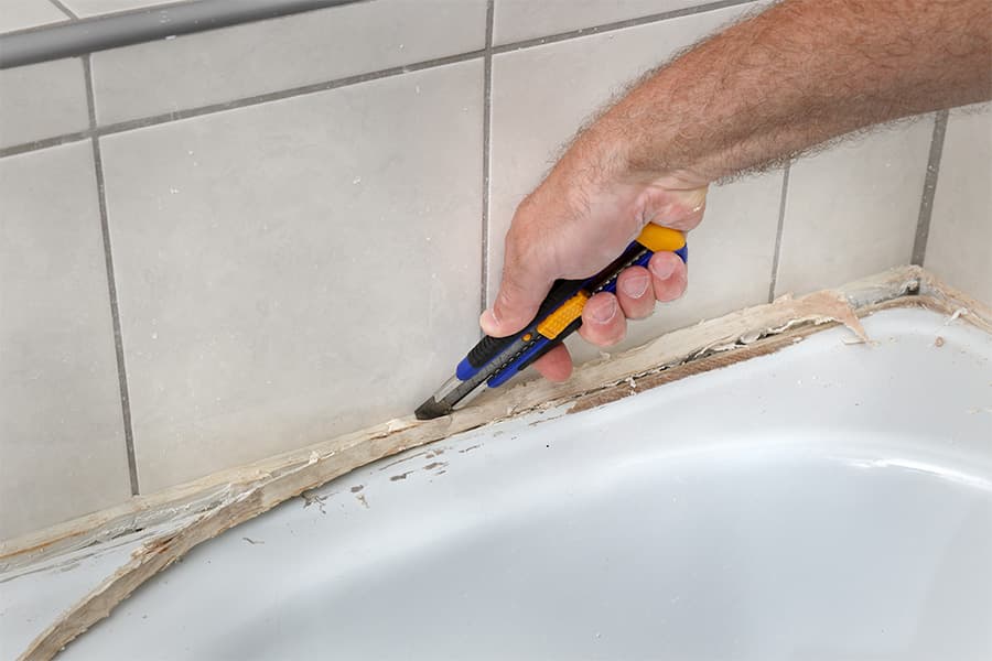 Bath sealant being removed with a safety knife.