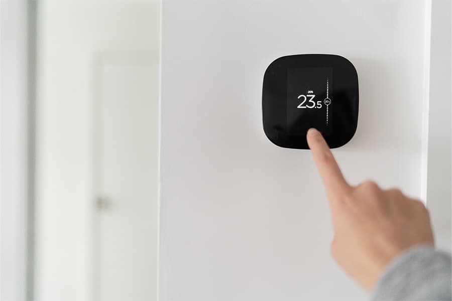 A modern, wireless smart thermostat hung on a wall.